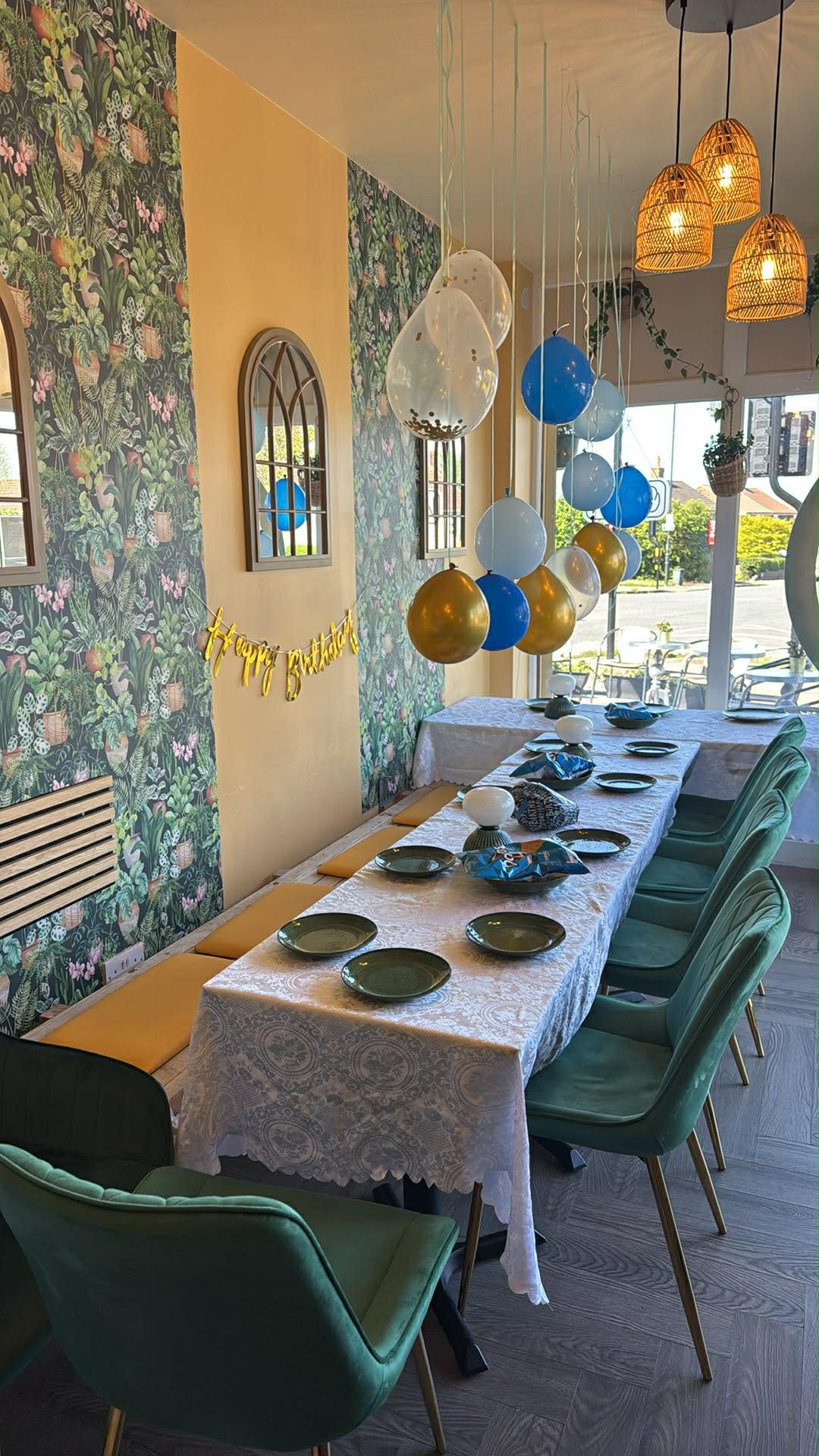 Birthday party setup at Bright's Cafe Bristol — balloons, lace tablecloth and green velvet chairs